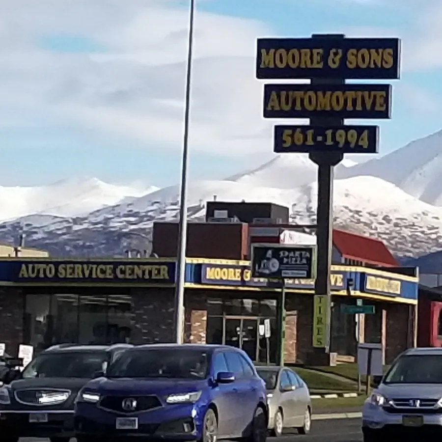 The Moore & Son's Automotive sign on East Dimond with the Chugach Mountains behind it
